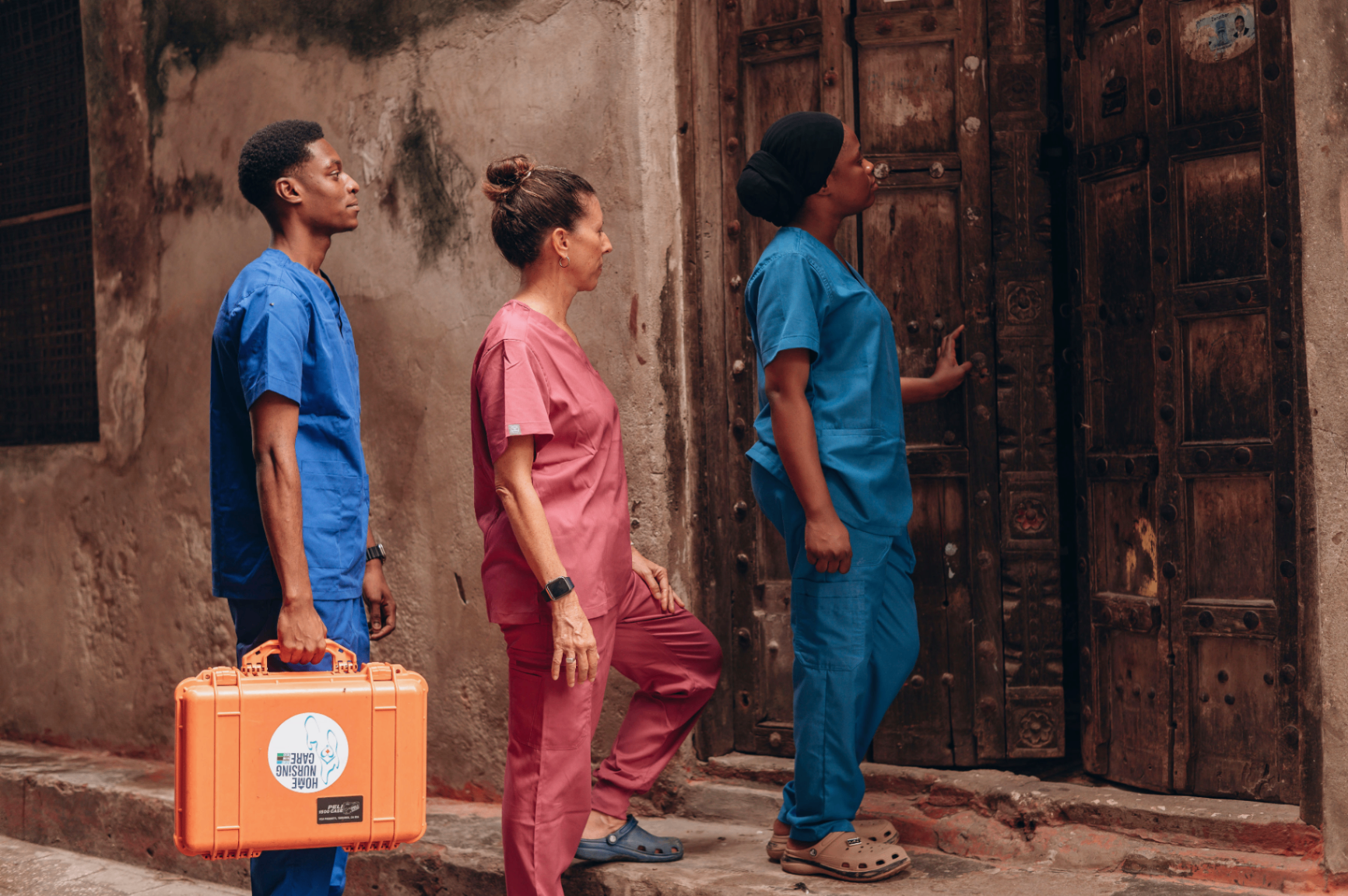 Three home nursing care nurses at a patient's door in Zanzibar